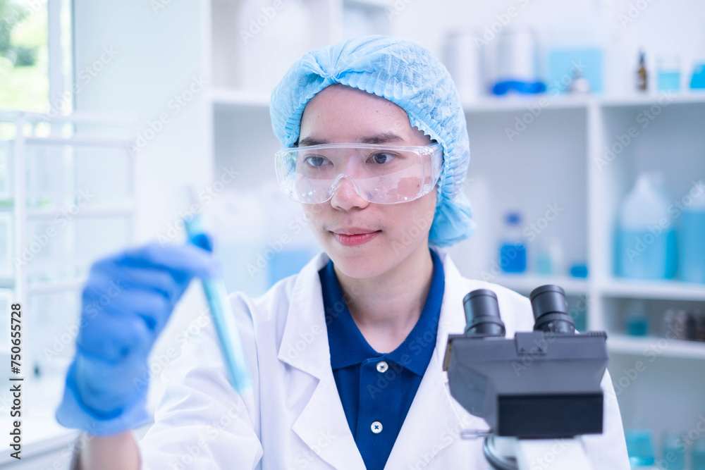 Closeup female woman scientist's hand holding blue liquid chemical chemistry test tube working in analyze science laboratory research experiment Closeup female woman scientist's hand holding blue liquid chemical chemistry test tube working in analyze science laboratory research experiment