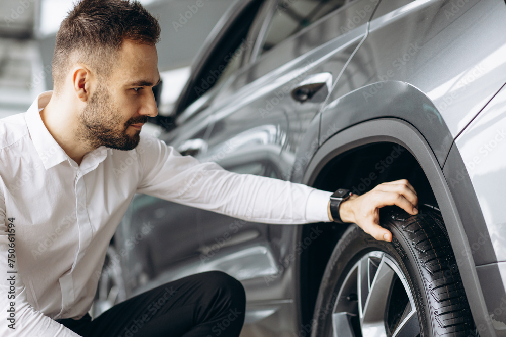 Man checking tires in new car in car showroom Man checking tires in new car in car showroom