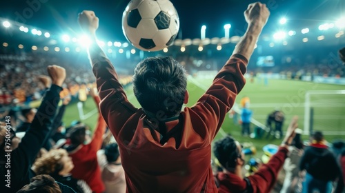 A man holding a soccer ball above his head in a display of triumph and victory on the soccer field