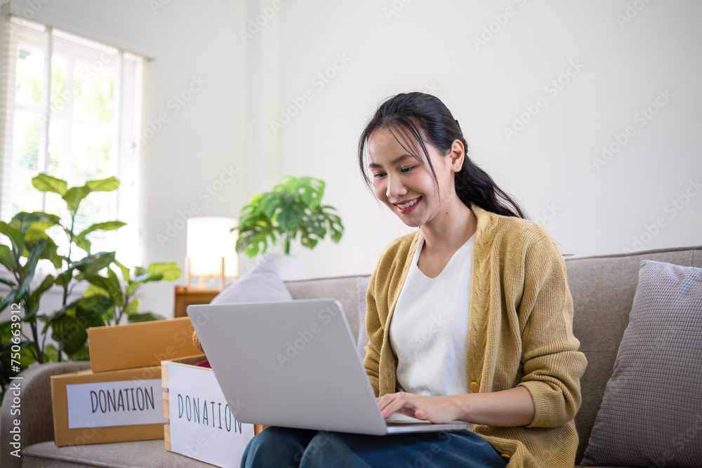 Asian woman uses laptop to search for clothing donation options to pass on unused clothing to others Asian woman uses laptop to search for clothing donation options to pass on unused clothing to others