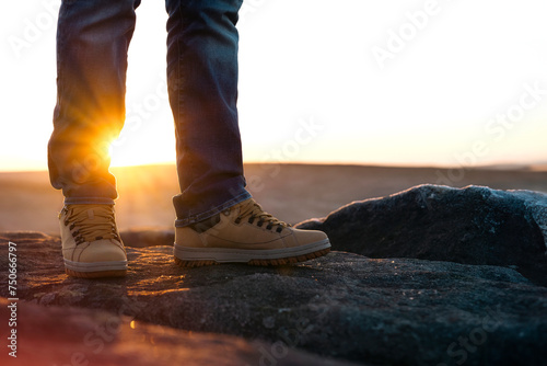 closeup of feet of man in special boots walking in the mountains reaching the destination and on the top of mountain at sunrise or sunset. Travel Lifestyle concept