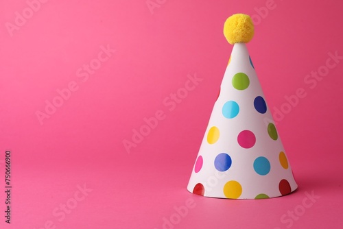 One beautiful party hat with pompom on pink background, space for text