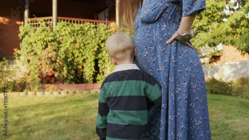 Little boy hearing his pregnant mom's belly outdoor  photo