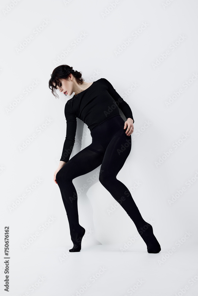 Obraz premium Full-length image of passionate, artistic young woman with smoky eyes makeup, black clothes standing in dynamic pose against white studio background. Concept of fashion, beauty, emotions
