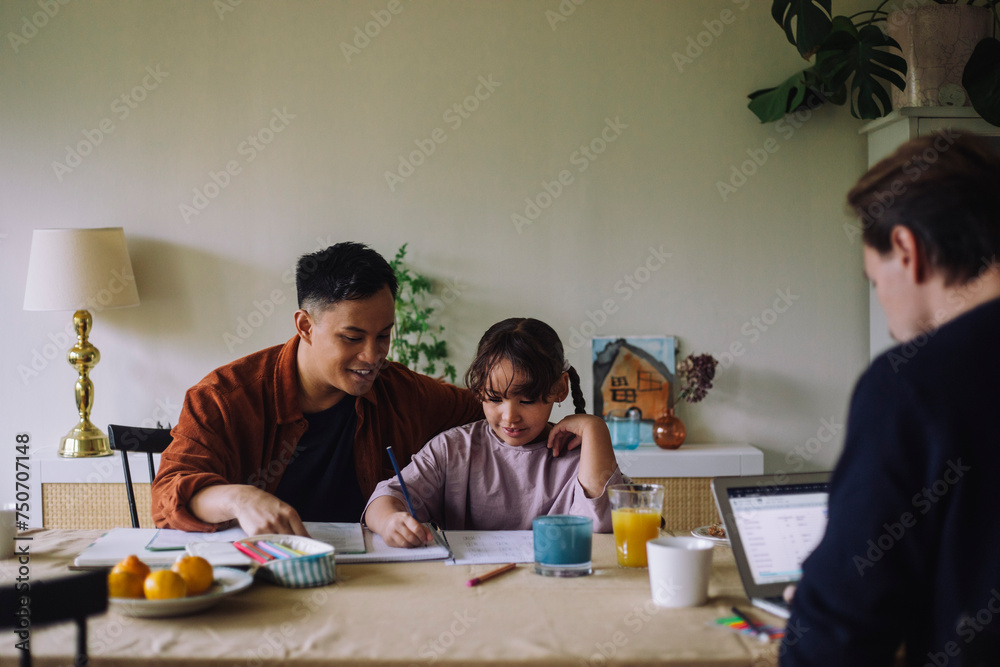Gay father assisting daughter while doing homework at home Gay father assisting daughter while doing homework at home