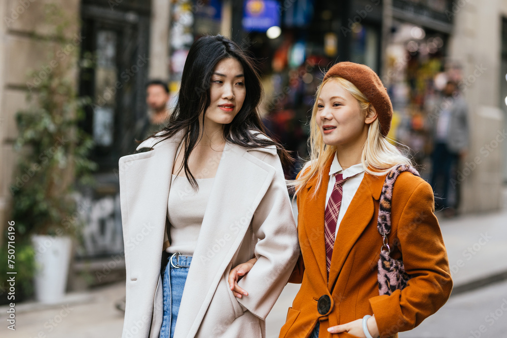 Two stylish young women walking on the street together.