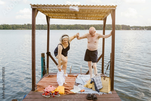 Full length of senior man helping woman in removing shorts at gazebo photo