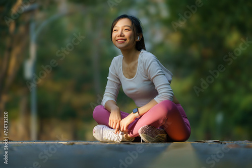 A woman practices yoga exercises in a serene park surrounded by nature, grass, and greenery, embodying relaxation, meditation, and a healthy lifestyle.
