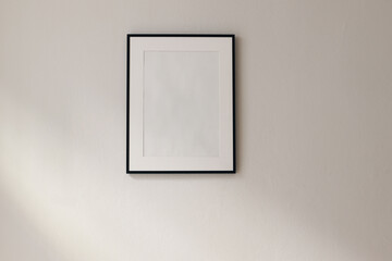 Artistic mockup template. Black vertical picture frames on beige wall background in sunlight. Poster display at home, minimal Scandinavian design, no people. Elegant apartment concept. Template