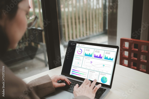 Businesswoman working on laptop with business dash board analytics chart metrics KPI to analyze the performance and create insign reports of business management. Data science concept. photo