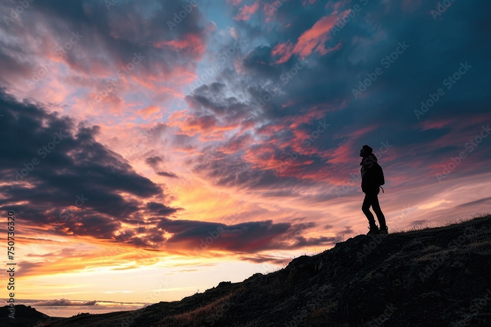 the silhouette of a person standing on a hill, surrounded by a breathtaking sunset, with the colorful sky and clouds dominating the frame the silhouette of a person standing on a hill, surrounded by a breathtaking sunset, with the colorful sky and clouds dominating the frame