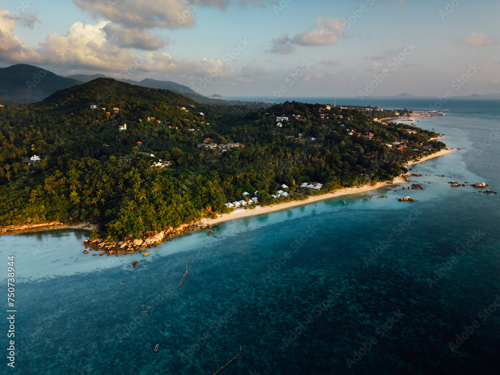 This bird's-eye view reveals a beautiful tropical island. Surrounded by clear turquoise water like glass. The pristine white beaches contrast with the lush greenery of the island's greenery. In the ce