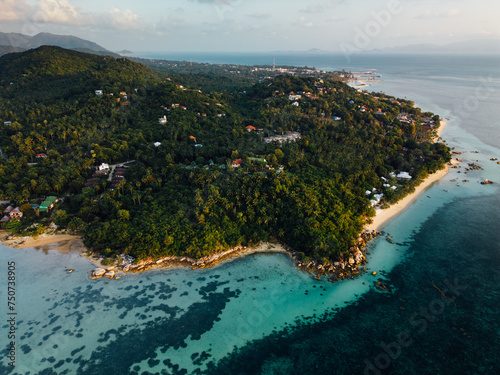 This bird's-eye view reveals a beautiful tropical island. Surrounded by clear turquoise water like glass. The pristine white beaches contrast with the lush greenery of the island's greenery. In the ce