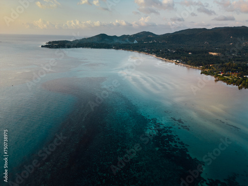 This bird's-eye view reveals a beautiful tropical island. Surrounded by clear turquoise water like glass. The pristine white beaches contrast with the lush greenery of the island's greenery. In the ce