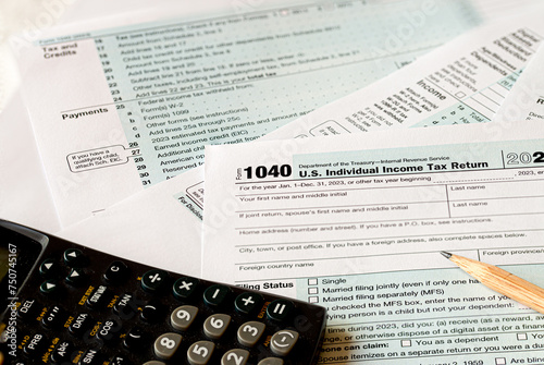 IRS 1040 tax form with calculator and pencil on a table. Tax time USA. © Bert