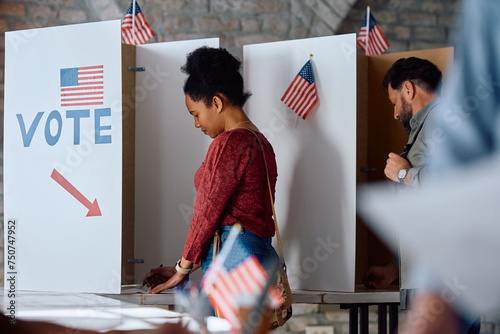 Black female citizen voting at polling station during elections in USA.