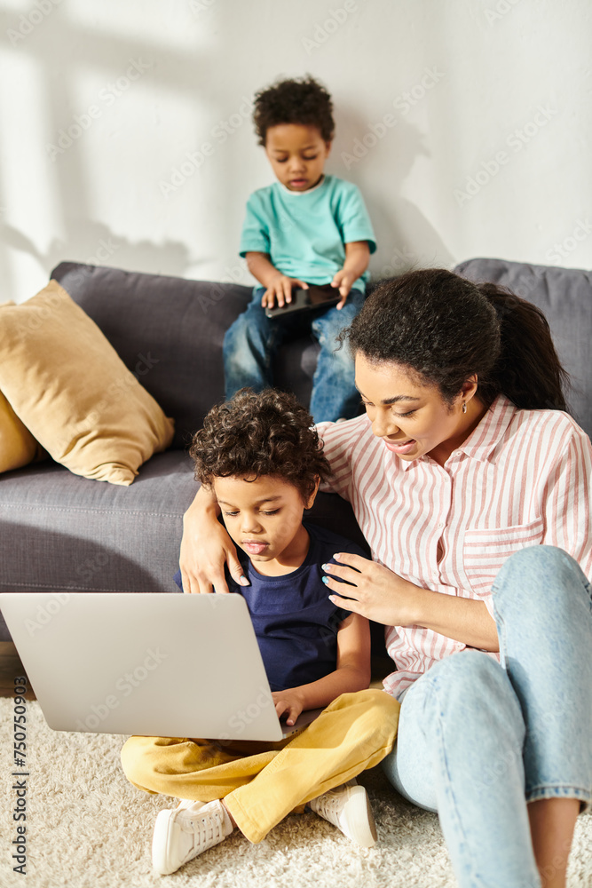 joyous african american woman spending time with her two jolly cute sons holding laptop and phone joyous african american woman spending time with her two jolly cute sons holding laptop and phone