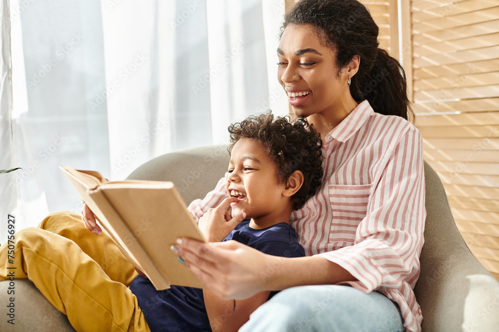 Obraz premium joyous beautiful african american woman reading interesting book with her little adorable son