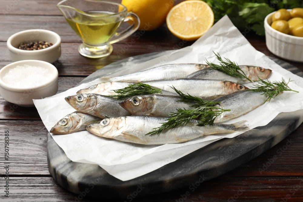Fresh raw sprats, dill and other products on wooden table, closeup Fresh raw sprats, dill and other products on wooden table, closeup