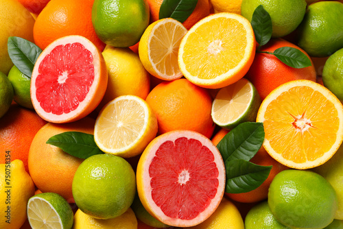 Different fresh citrus fruits and leaves as background, top view