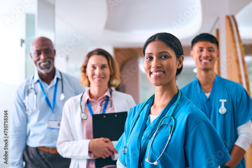 Portrait Of Smiling Multi Cultural Medical Team Wearing Scrubs And White Coats In Modern Hospital 