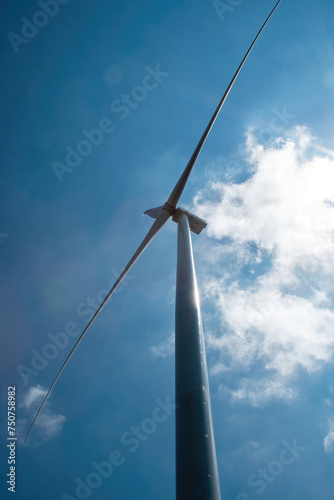 Thin windmill rotor blades against sky and white cloud. Windmill producing renewable form of clean energy from wind low angle shot
