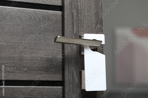 Wooden door with blank hanger on metal handle, closeup photo