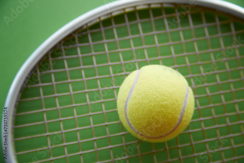yellow tennis ball lies on a tennis racket on a green background