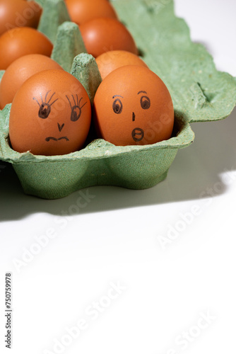 chicken eggs with painted faces on white background, vertical