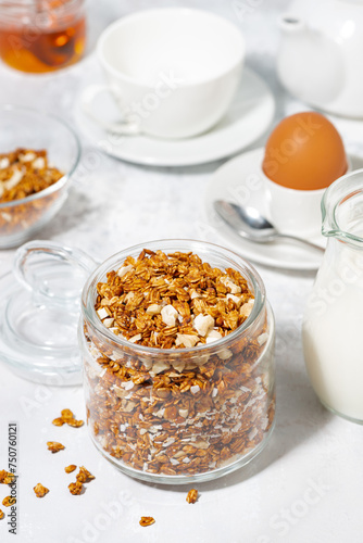 jar of granola with coconut and nuts on white background, vertical top view