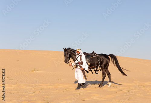 Saudi man in a desert with his black stallion