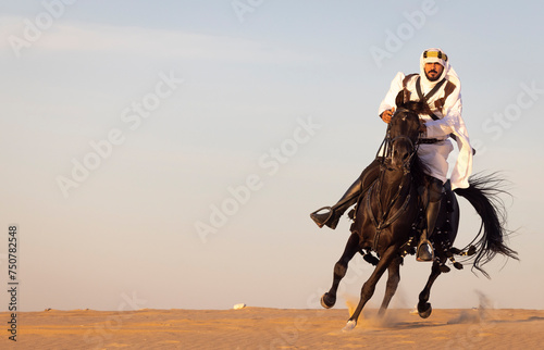 Saudi man in teaditional clothing riding a black horse in a desert