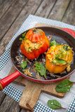 Zapiekane pomidory faszerowane polentą podane na żeliwnej czerwonej patelni.