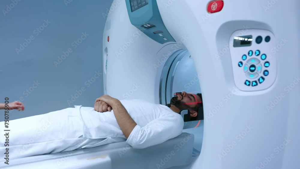 Doctor processing MRI procedure in clinic. Man lying on CT scanner during machine imaging body, lights up infrared rays and passes through circle, crane shot from down to up, room interior.