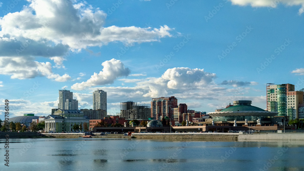 Buildings on the riverbank under a cloudy landscape