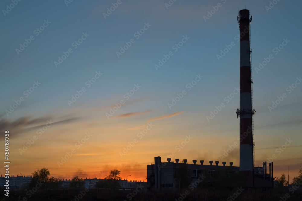 Boiler room with a tall chimney at dusk the backdrop of a picturesque sky at sunset