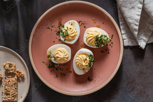 Deviled eggs with spicy oil and herbs, flatbread crackers, Easter party appetizer, directly above