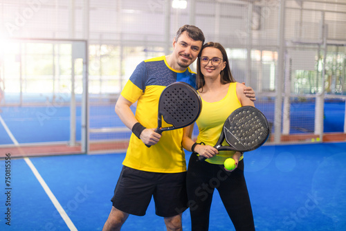 Family team mx. Group of two mix padel tennis players with racket. Woman and man athletes with paddle racket on the blue court. Sport concept. Download a high quality photo for a sports app.
