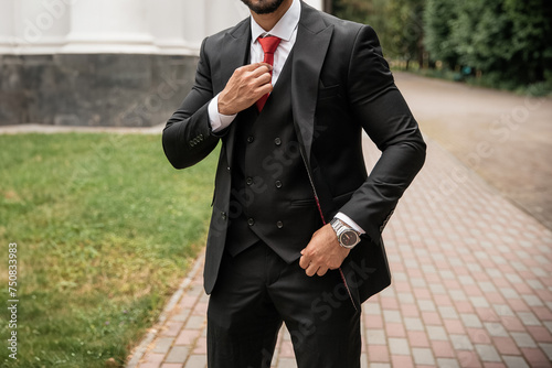 Stylish man in black luxury casual suit with red tie and expensive watch