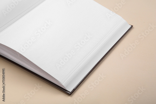 Open photo album on beige background, closeup. Space for text
