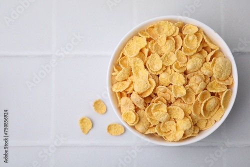 Breakfast cereal. Tasty crispy corn flakes in bowl on white tiled table, top view. Space for text
