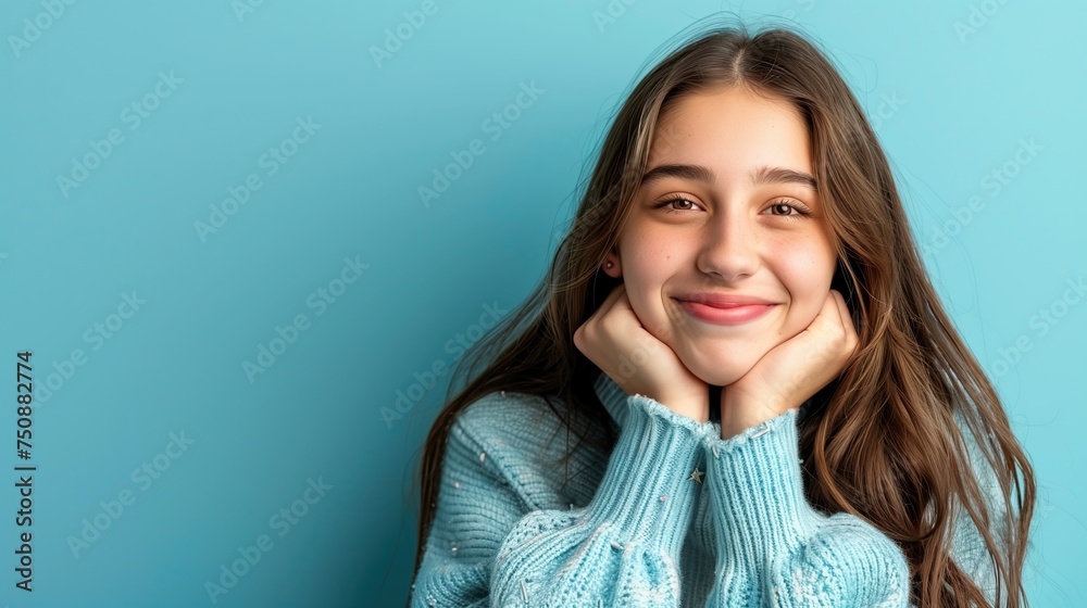 Smiling Teenage Girl in Blue Winter Jumper, Blue Studio Background, Copy Space For Text Smiling Teenage Girl in Blue Winter Jumper, Blue Studio Background, Copy Space For Text