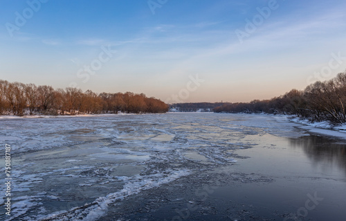 Ice floats on the water, frosty evening, cold, winter landscape with a wide river.