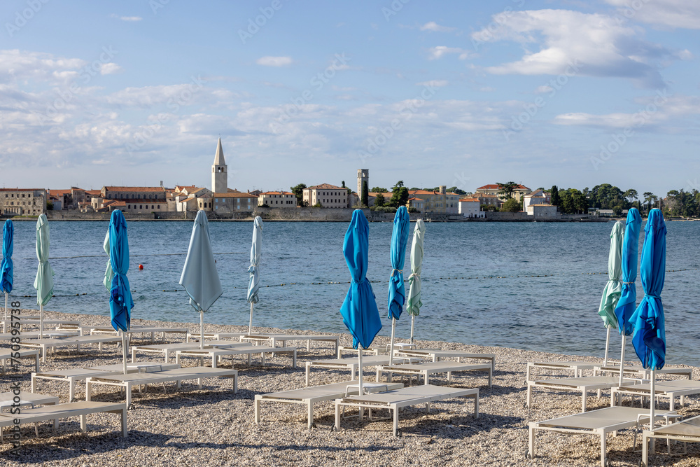 View from the beach with umbrellas of the city with the bell tower of the Basilica of Euphrasius, Porec, Croatia, Istria