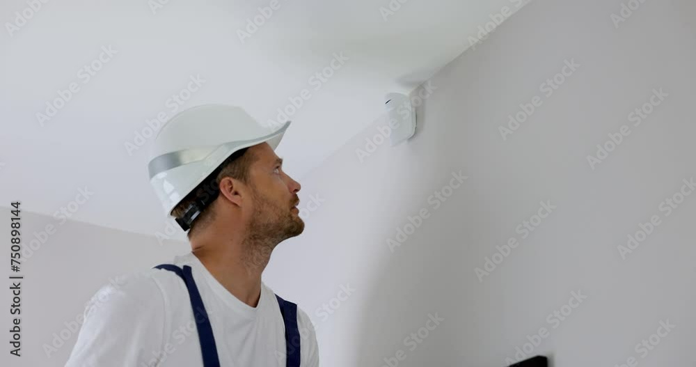 security system technician installing motion sensor on the wall at home
