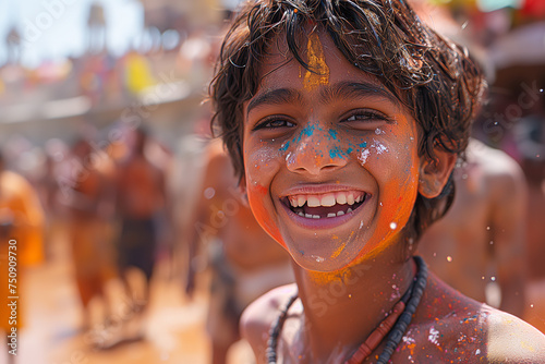 Little smiling and happy boy with colourful Holi powder on his face is celebrating Holi holiday. Selective focus. Copy space 
