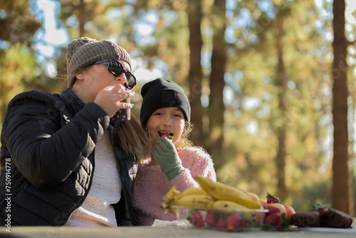 Mother with her daughter eating strawberries and drinking juice