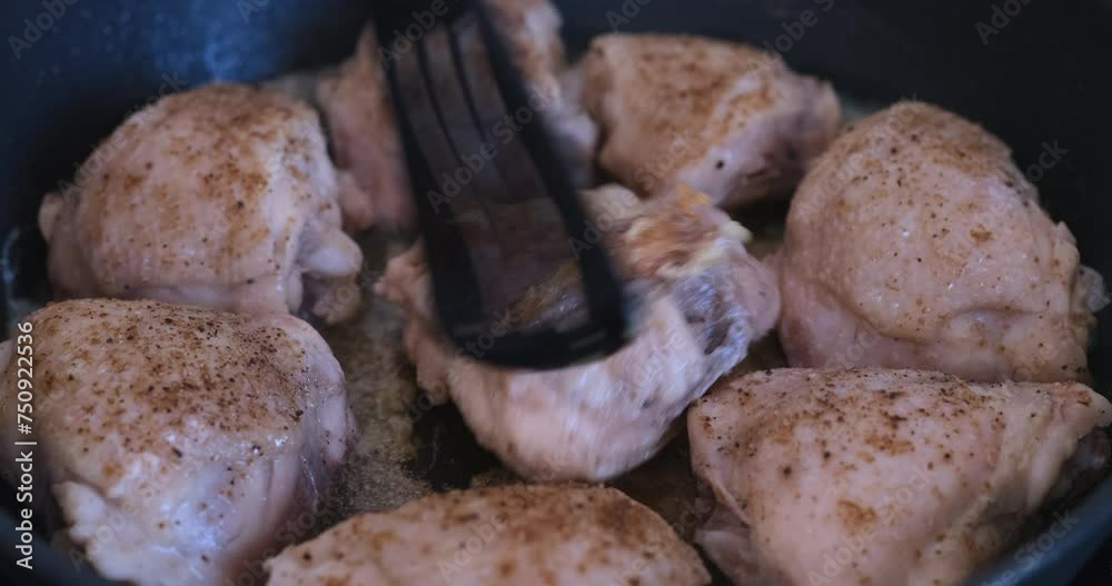 Chicken thighs being flipped over in a frying pan. Close up. Chicken thighs being flipped over in a frying pan. Close up.