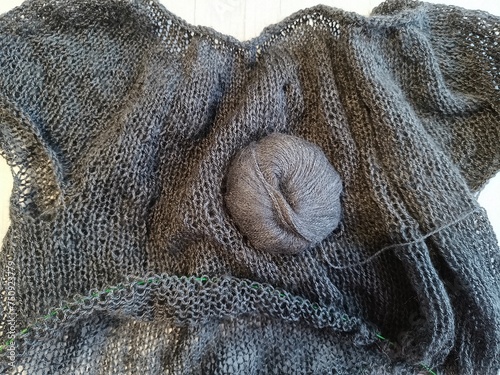 The process of knitting a jumper made of black and gray wool with sequins