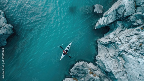 Aerial view of a kayaker navigating through calm turquoise waters among rugged cliffs